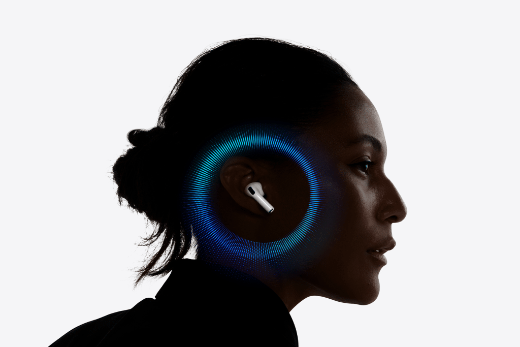 A woman in profile wears a wireless earbud, with a digital blue and purple circular graphic surrounding her ear, suggesting sound or U2 chip technology. The background is plain white.