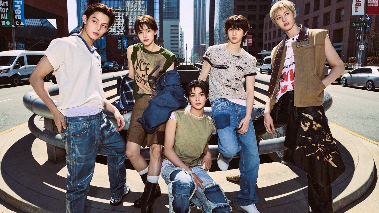 Five young men pose stylishly in trendy, casual outfits on a city street, surrounded by tall buildings and passing cars—capturing the confident spirit of urban life, as if ready to step into a Vision Pro immersive cinema experience.