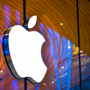 Large, illuminated Apple logo on the exterior of an Apple Store, set against a modern, curved wooden ceiling and reflective glass windows—a striking symbol amid discussions on the Digital Markets Act.