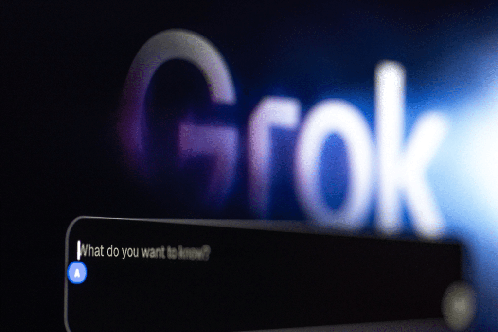 A computer screen shows the word "Grok" blurred in the background, with a chat box in the foreground displaying, "What do you want to know?"—highlighting an AI conversation powered by xAI Grok 4 from Elon Musk.