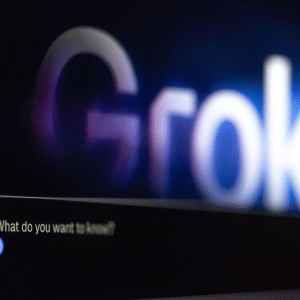 A computer screen shows the word "Grok" blurred in the background, with a chat box in the foreground displaying, "What do you want to know?"—highlighting an AI conversation powered by xAI Grok 4 from Elon Musk.