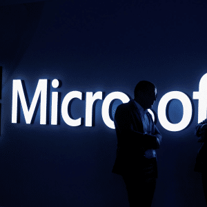 Two people stand in silhouette, talking in front of a brightly lit Microsoft logo on a dark background, highlighting the growing importance of AI infrastructure in today's tech landscape.