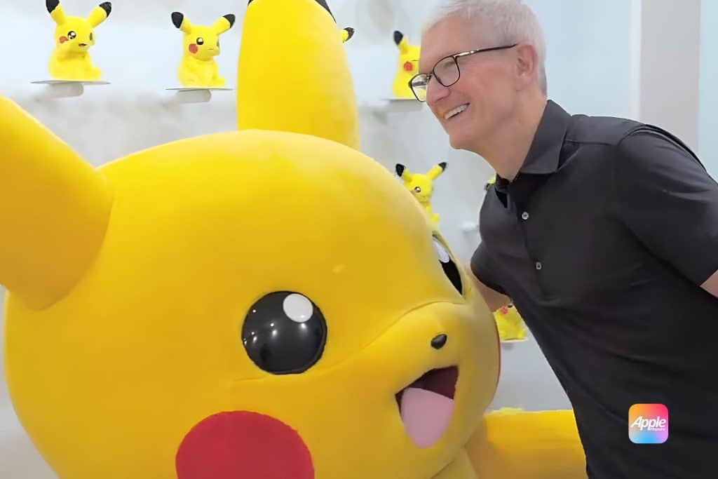 A man in a black shirt smiles while posing next to a large Pikachu mascot, with several smaller Pikachu figures on shelves in the background—capturing a true Tim Cook’s Pikachu Moment. An apple japanese logo is visible in the bottom right corner.