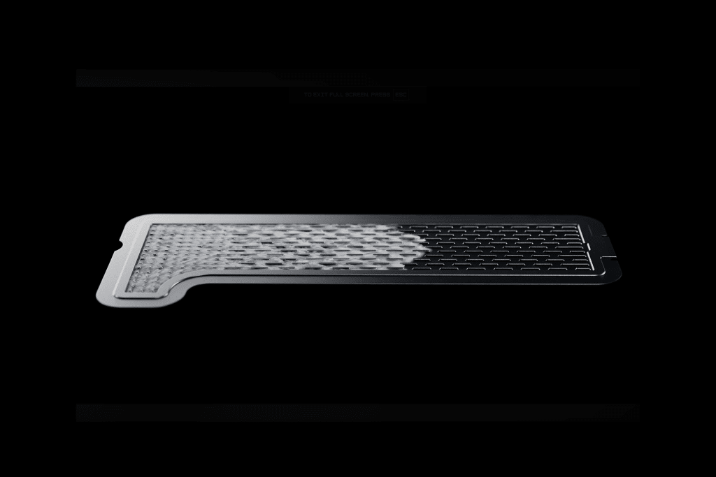 A thin, rectangular metal filter—resembling an iPhone Vapor Chamber—is shown on a black background. The left side appears partially covered with a textured, mesh-like material.