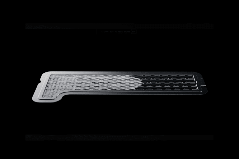 A thin, rectangular metal filter—resembling an iPhone Vapor Chamber—is shown on a black background. The left side appears partially covered with a textured, mesh-like material.