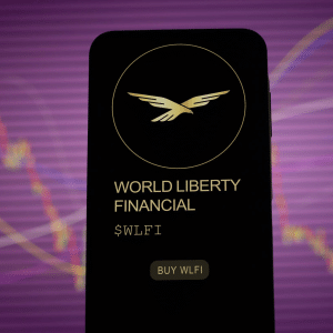 A smartphone screen displays the World Liberty Financial logo, name, ticker symbol $WLFI, and a "Buy WLFI" button—highlighting Apple Pay Crypto integration—against a blurred financial chart and purple background.