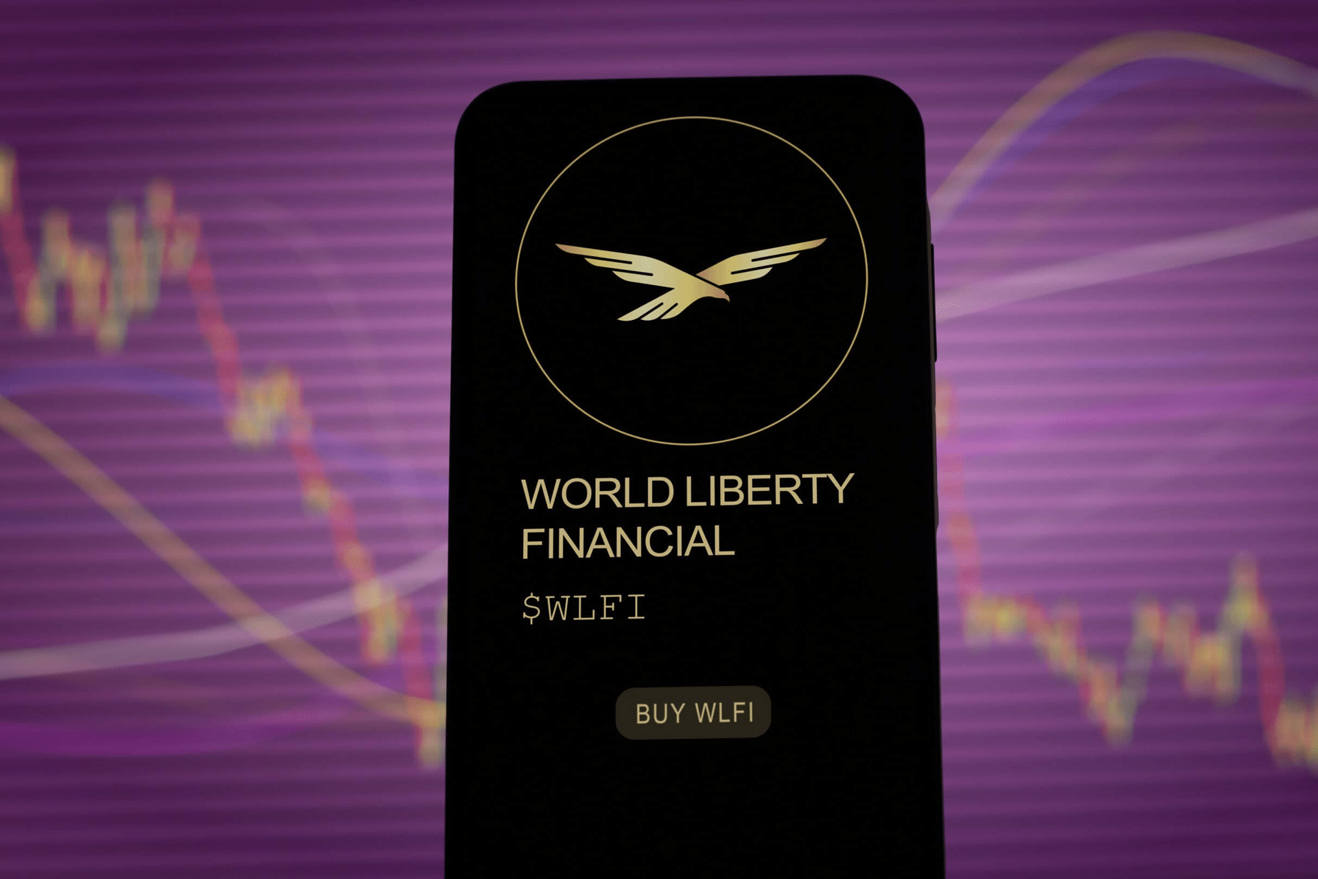 A smartphone screen displays the World Liberty Financial logo, name, ticker symbol $WLFI, and a "Buy WLFI" button—highlighting Apple Pay Crypto integration—against a blurred financial chart and purple background.