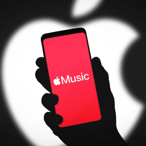 A hand holds a smartphone displaying the Apple Music app on a red screen, with a large blurred white Apple logo in the background, highlighting the swipe gesture used to switch tracks effortlessly.