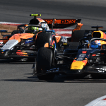 Two Formula 1 cars race closely around a bend on the track, their vibrant colors captured in stunning detail. This thrilling moment could be seen on the latest Apple F1 broadcast deal, with both helmeted drivers pushing to the limit.
