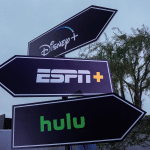 Three black directional signs point in different directions, each featuring the logos for Disney+, ESPN+, and Hulu—highlighting the Disney Hulu ESPN bundle—with trees and a cloudy sky in the background.