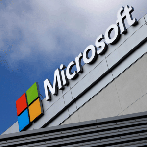 The Microsoft logo and name are displayed on the exterior of a modern building against a partly cloudy sky, subtly highlighting conversations around Microsoft unfair software pricing.