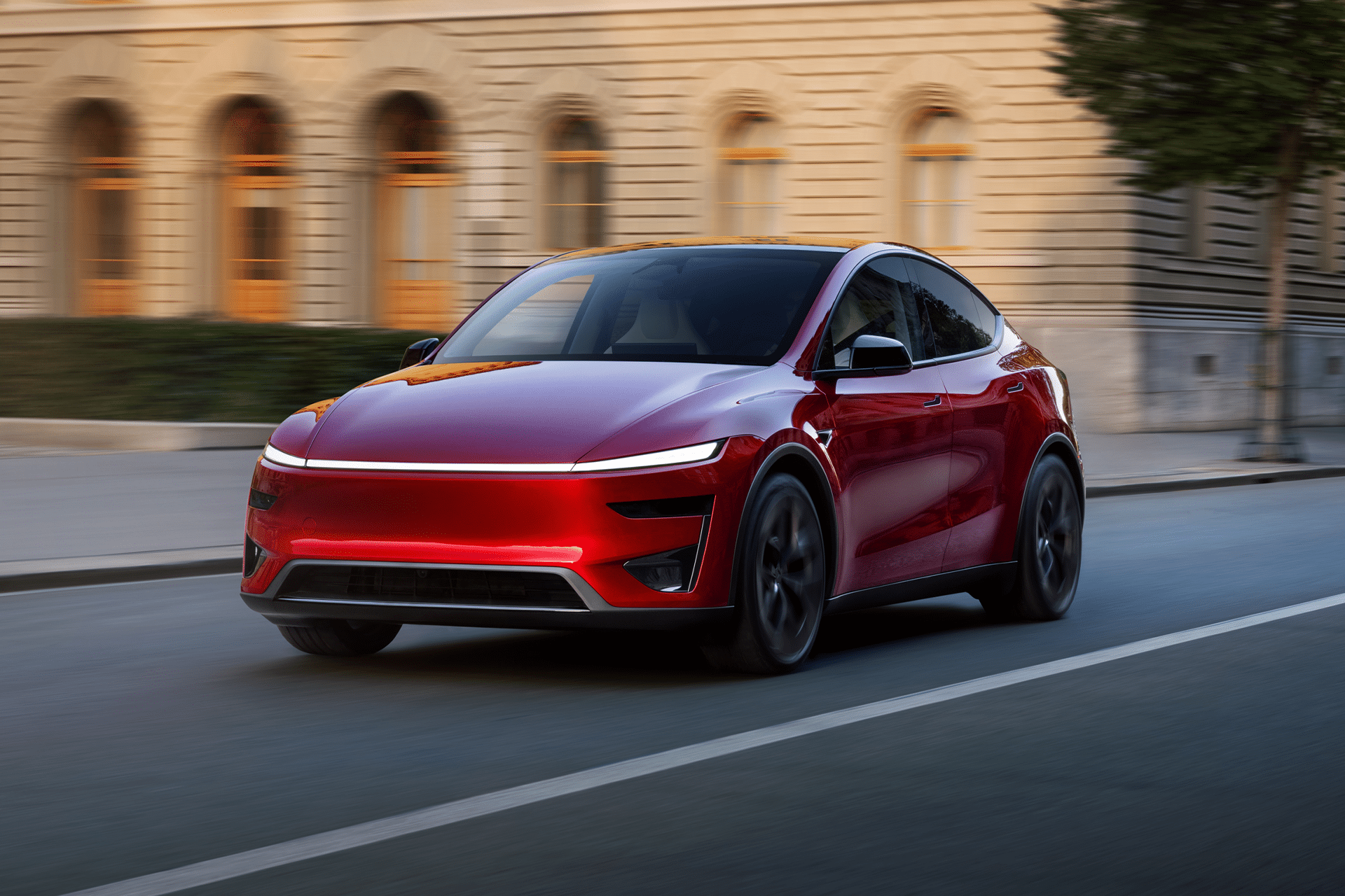 A sleek, red electric car with tinted windows glides down a city street, passing elegant stone buildings. Its modern design with smooth lines and black wheels stands out—catch it before the EV tax credit ending impacts your savings.