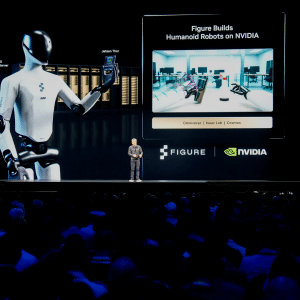 A speaker stands on stage presenting to a large audience, with a screen behind showing a humanoid robot and the logos of Figure and NVIDIA, highlighting their vision for an Nvidia robot workforce shaping the future.