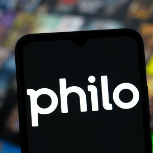 A smartphone screen displays the Philo logo in white text, with a blurred background featuring colorful, out-of-focus streaming content thumbnails, including references to Philo HBO Max favorites.