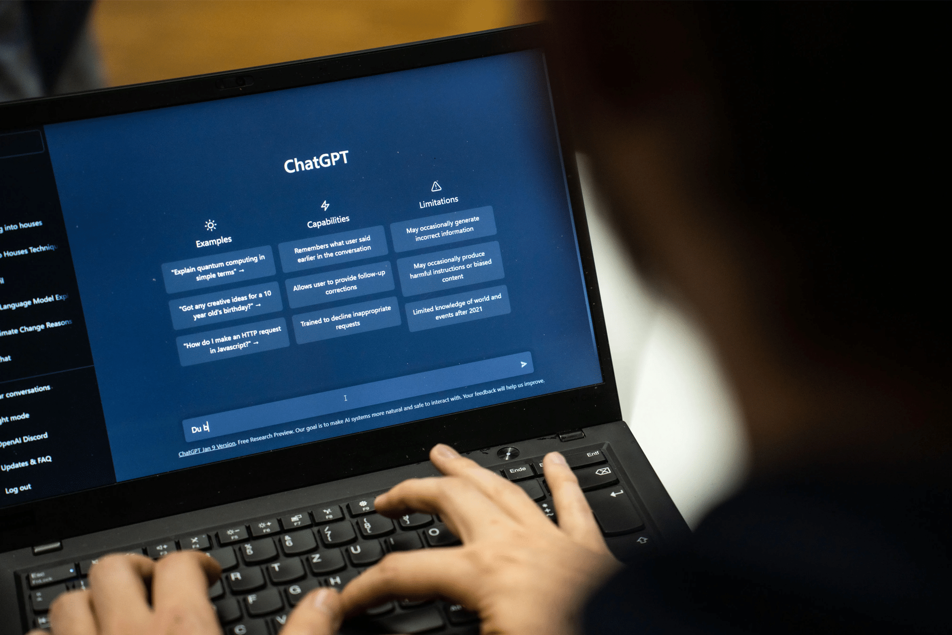 A person types on a laptop displaying the ChatGPT interface—ideal for computer science graduates exploring the job market—showing sections for Examples, Capabilities, and Limitations on a dark screen.