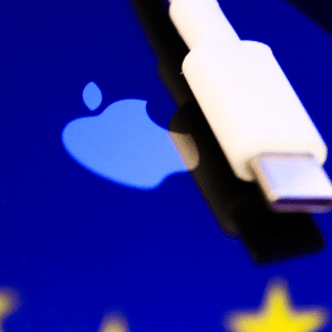 A white USB-C connector rests on a blue surface displaying the Apple logo and part of yellow stars, subtly evoking the ongoing Apple EU dispute over charging standards and regulations.