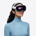 A person wearing a sleek Vision Pro headset powered by the advanced M5 chip and a light blue, long-sleeved turtleneck top stands against a plain white background.