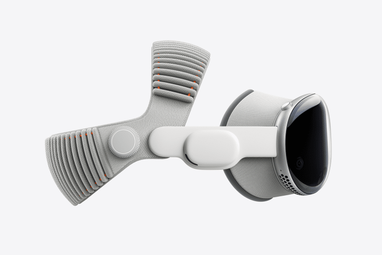 Side view of a sleek, modern virtual reality headset featuring the advanced Vision Pro M5 chip, with a white and gray fabric strap, rounded edges, and a smooth, reflective front surface. The design is accented with orange details on the strap.