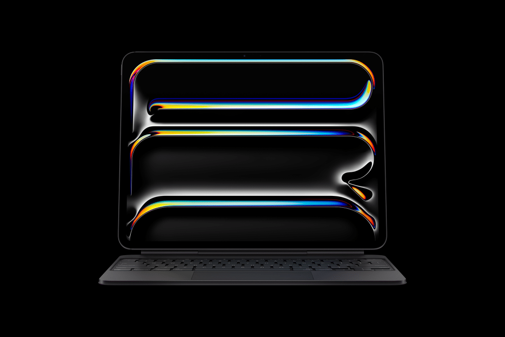 A sleek, black laptop with a keyboard attached displays a dark screen featuring colorful, fluid, neon-like lines—reminiscent of an iPad Pro M5 chip’s vibrant visuals—forming rectangular and oval shapes against a black background.