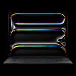 A sleek, black laptop with a keyboard attached displays a dark screen featuring colorful, fluid, neon-like lines—reminiscent of an iPad Pro M5 chip’s vibrant visuals—forming rectangular and oval shapes against a black background.