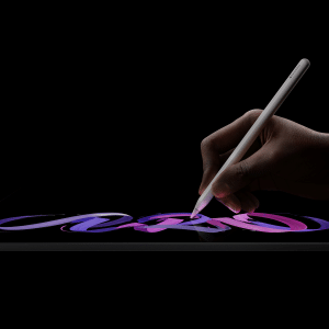 A hand uses a stylus to draw vibrant, colorful strokes on an iPad Pro M5 chip tablet against a black background.