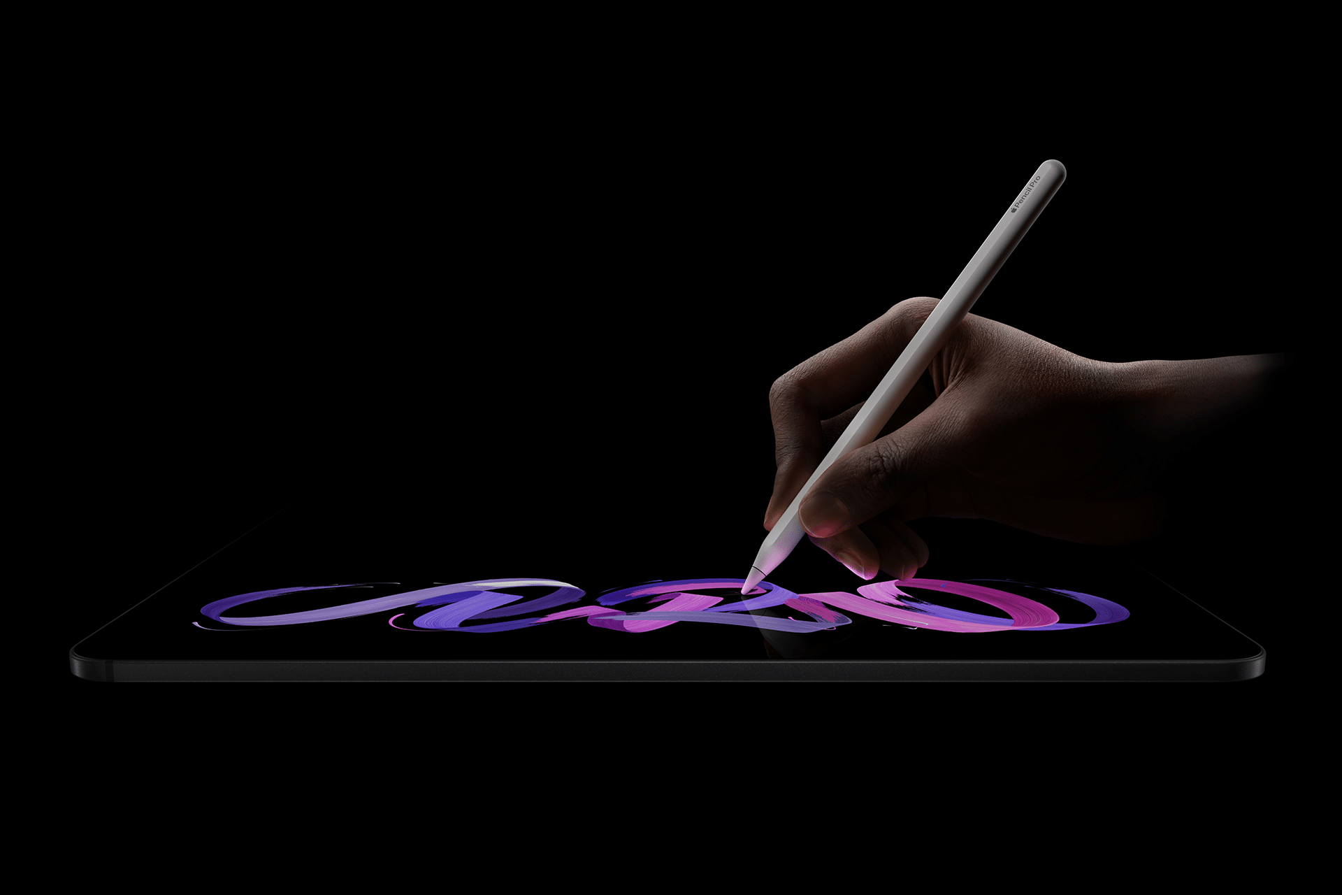 A hand uses a stylus to draw vibrant, colorful strokes on an iPad Pro M5 chip tablet against a black background.