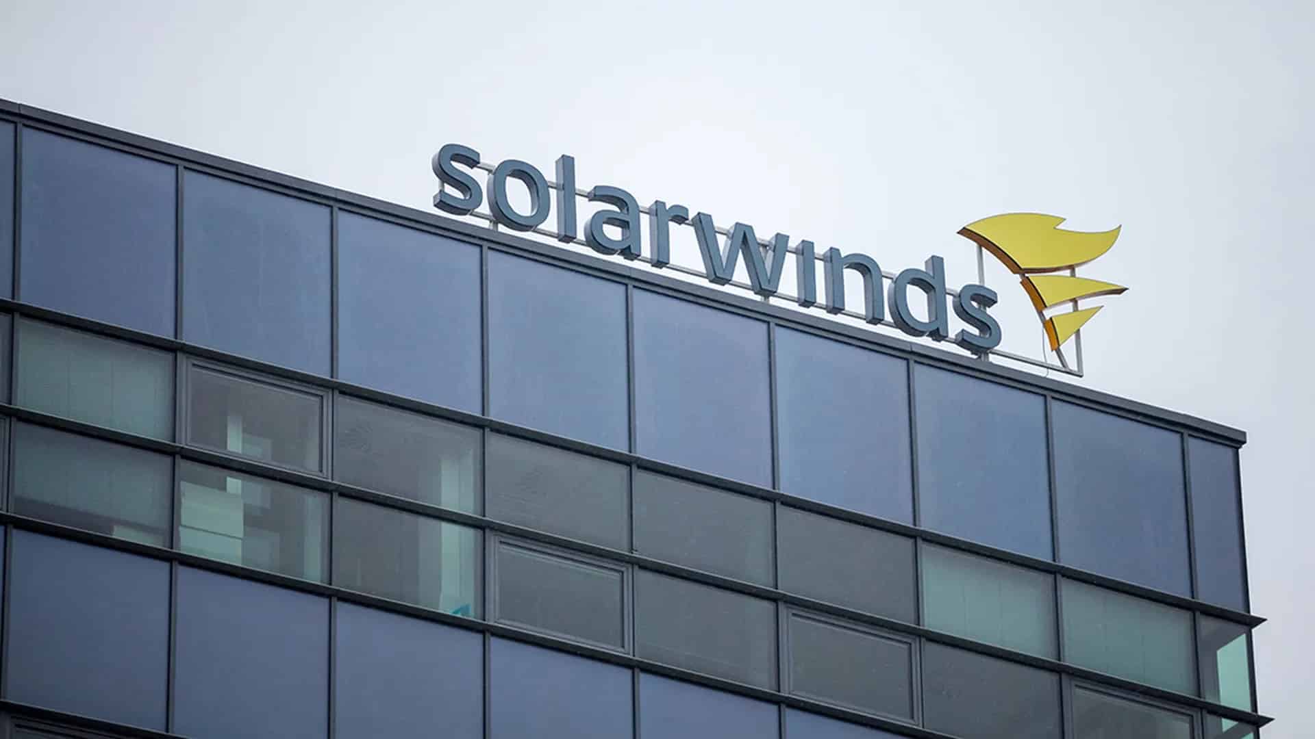 The exterior of a modern glass building with the SolarWinds company logo and name displayed on the rooftop against a cloudy sky, highlighting the site at the center of the SEC lawsuit following the SolarWinds hack.