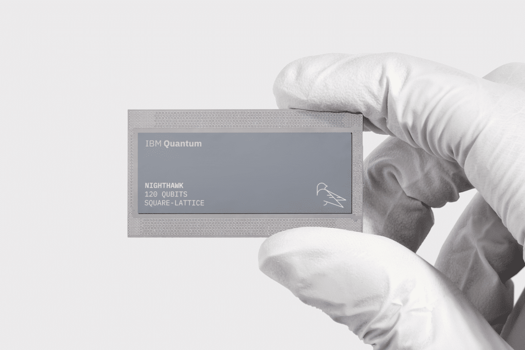 A gloved hand holds a rectangular IBM Quantum chip labeled "Nighthawk, 127 qubits, square-lattice" on a plain light background, amid swirling Apple quantum computing rumor discussions.