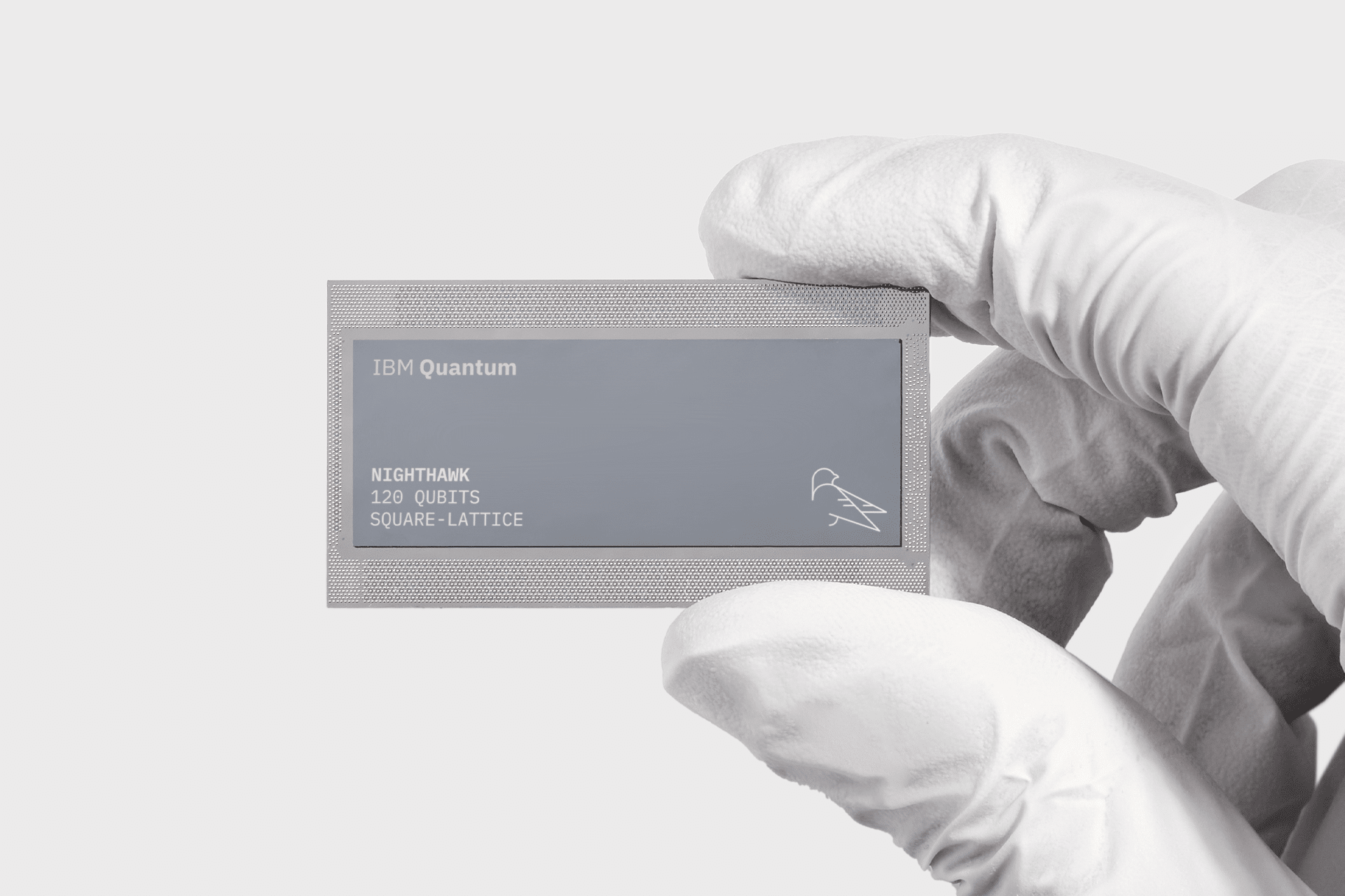 A gloved hand holds a rectangular IBM Quantum chip labeled "Nighthawk, 127 qubits, square-lattice" on a plain light background, amid swirling Apple quantum computing rumor discussions.