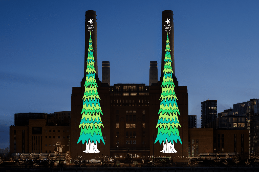 A brick power station at night with two tall chimneys, each brightly lit for the Apple Christmas tree challenge—adorned with cartoon-style Christmas trees topped by stars. The cityscape glows in the background.