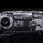 A close-up, cross-section view of a smartphone’s internal components—highlighting a large camera lens, circuitry, and chips—showcases the Apple logo in the bottom right corner and hints at advanced Apple 3D printing technology.