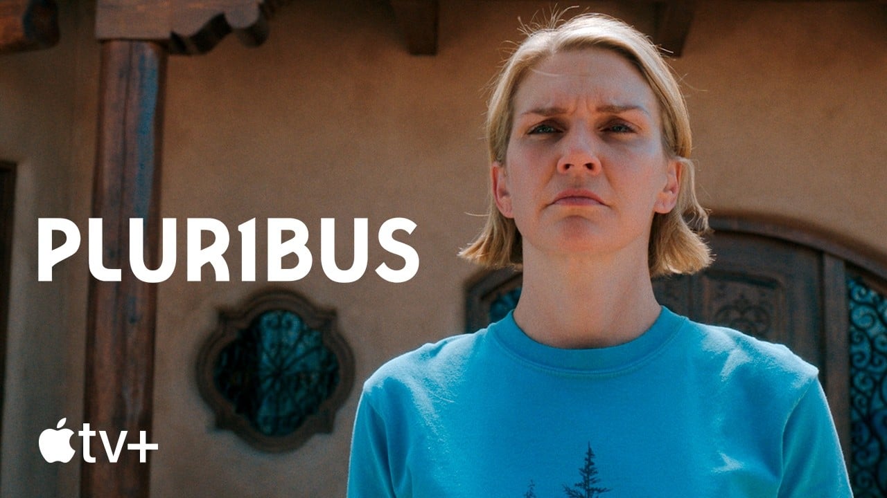 A woman with short blond hair stands outside a building with a serious expression. The word "PLUR1BUS" appears beside her, and the Apple TV+ logo is at the bottom left.