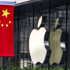 A large Apple logo is displayed on the glass facade of an Apple store, with a Chinese flag featuring five yellow stars on a red background hanging in the foreground, highlighting iPhone Singles Day excitement in China.