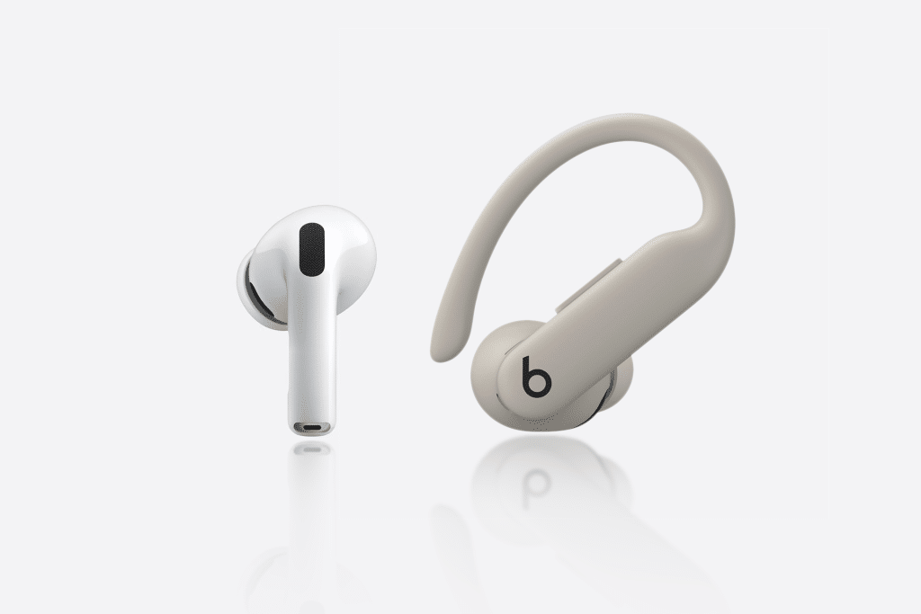 A white wireless earbud and a beige over-ear hook earbud with a "b" logo are displayed side by side, highlighting the design differences between AirPods Pro 3 vs Powerbeats Pro 2 on a clean white background.