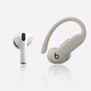 A white wireless earbud and a beige over-ear hook earbud with a "b" logo are displayed side by side, highlighting the design differences between AirPods Pro 3 vs Powerbeats Pro 2 on a clean white background.