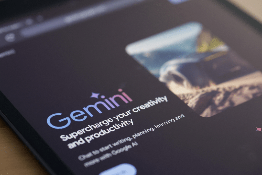 A tablet screen displays the Gemini AI homepage with the text, "Gemini: Supercharge your creativity and productivity," next to a blurred image and a dark background, highlighting its recent iOS AI expansion.