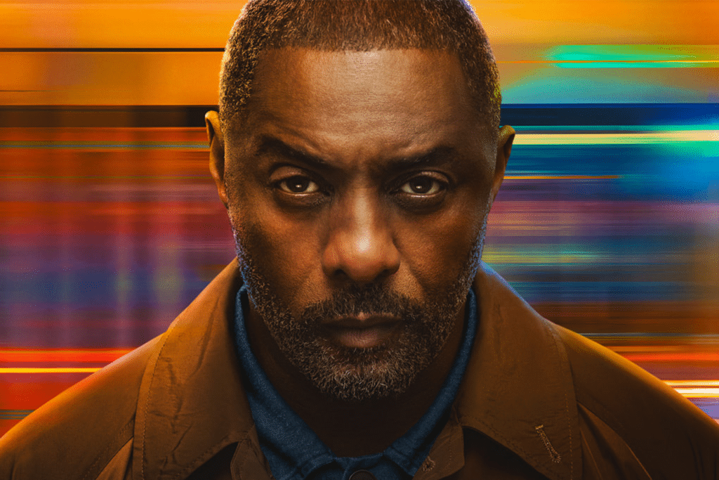 A man with a serious expression, closely cropped hair, and a short beard stands against a blurred, colorful background reminiscent of the intense visuals seen in the hijack season 2 trailer.