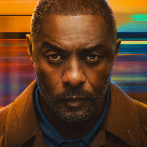 A man with a serious expression, closely cropped hair, and a short beard stands against a blurred, colorful background reminiscent of the intense visuals seen in the hijack season 2 trailer.