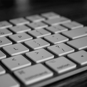 A close-up, black and white image of a Magic Keyboard focusing on the central letter and symbol keys, with shallow depth of field and a blurred background.