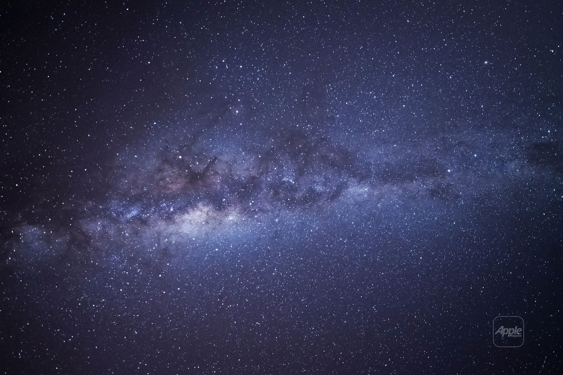 A wide view of the night sky, as seen in AppleMagazine's Happy New Year 2026 issue, shows the Milky Way galaxy filled with countless stars and cosmic dust stretching diagonally across a dark, purple-blue background.