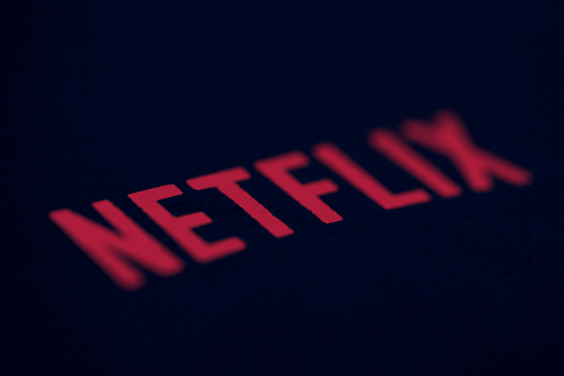 Close-up of the red Netflix logo in uppercase letters on a dark background, highlighting recent updates like Netflix Google Cast Support Removed.