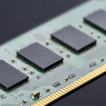 A close-up view of a computer RAM module, highlighting four black memory chips on a green circuit board with gold connector pins—an example of hardware impacted by the recent RAM price surge.
