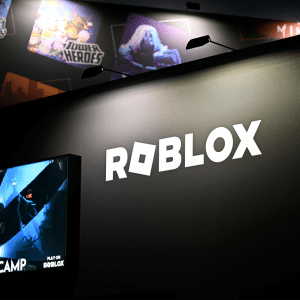 A large black display features the ROBLOX logo in white letters. Below, a screen shows the game "Dread Camp" with animated characters—highlighting ROBLOX’s popularity even amid Russia internet restrictions. Posters of other games are partially visible in the background.