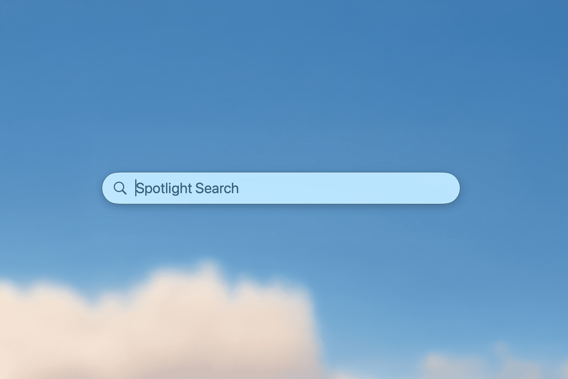 A Spotlight Search bar appears centered on a clear blue sky background with a few soft clouds at the bottom, perfect for discovering new Spotlight search tips on your Mac.