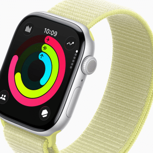 A close-up of a smartwatch with a light yellow fabric band, displaying colorful activity rings and the time “10:09” on its screen—perfect for tracking your first day fitness+ goals. The silver case features a round side button and digital crown.