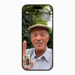 A smiling older man in a flat cap is on a Facetime video call, holding up his index finger. He is outside with greenery behind him. A small inset shows another smiling man on the call. Text instructions appear at the top of the screen.