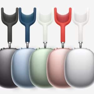 Five AirPods Max headphones in black, blue, green, pink, and silver are displayed upright in a row on a white background with the Apple logo in the lower right corner.