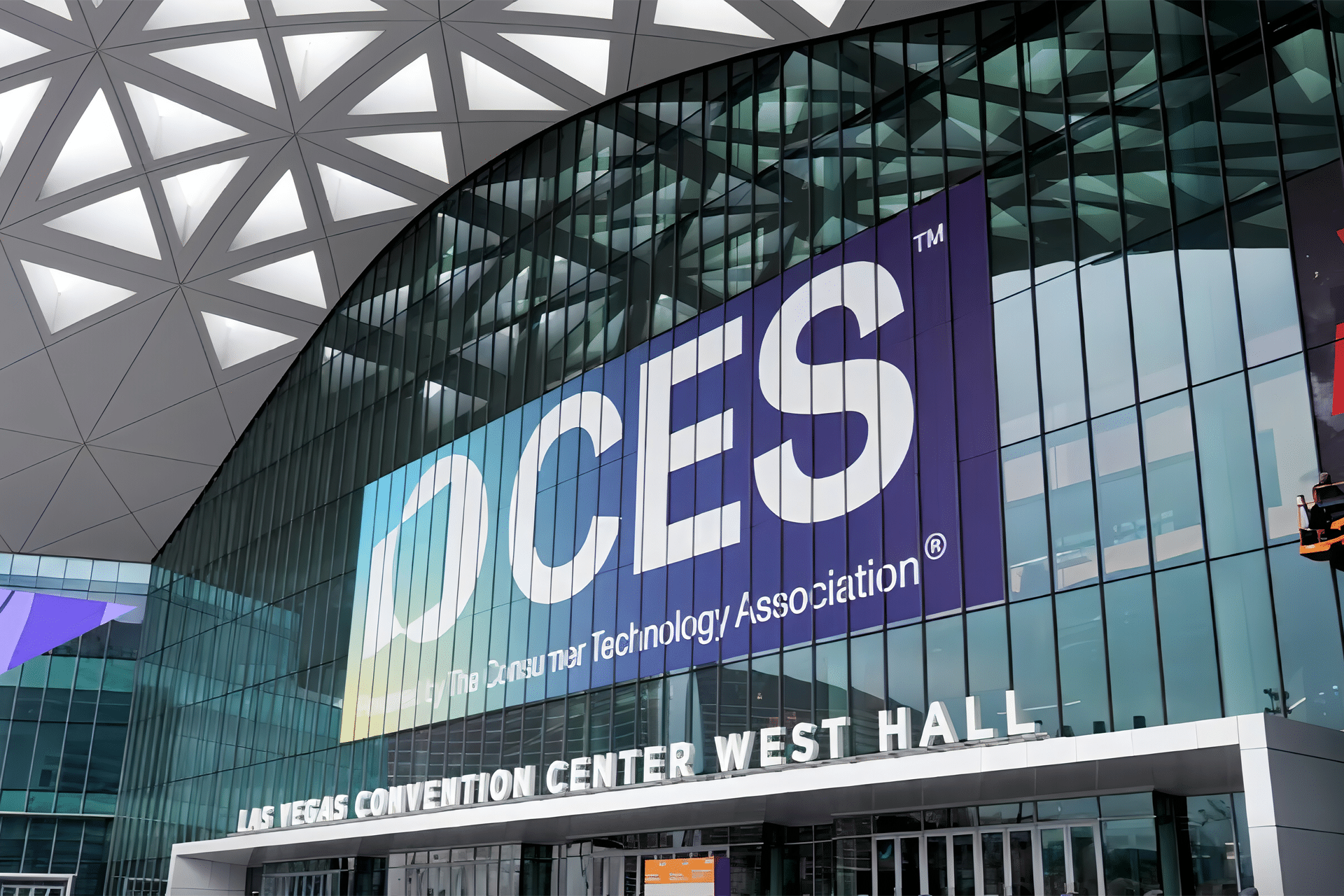 The exterior of the Las Vegas Convention Center West Hall, featuring a large CES 2026 displayed on glass windows under a geometric patterned roof, draws anticipation for innovations from brands like Apple.