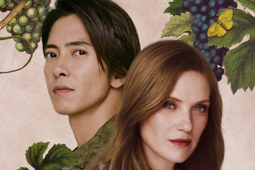 A man with straight black hair and a woman with long, light brown hair stand close together in front of a floral background with green grapevines, leaves, grapes, and a yellow butterfly—reminiscent of the elegant visuals in Apple TV Drops of God.