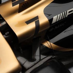 Close-up of a Formula 1 car’s bodywork in black and gold, showing the number 7, AMG logo, MSC branding, and aerodynamic parts with sleek lines and carbon fiber details—perfect for any Apple TV F1 fan.